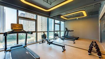 A gym with treadmills, rowing machines, and dumbbells, large windows, and a modern design.