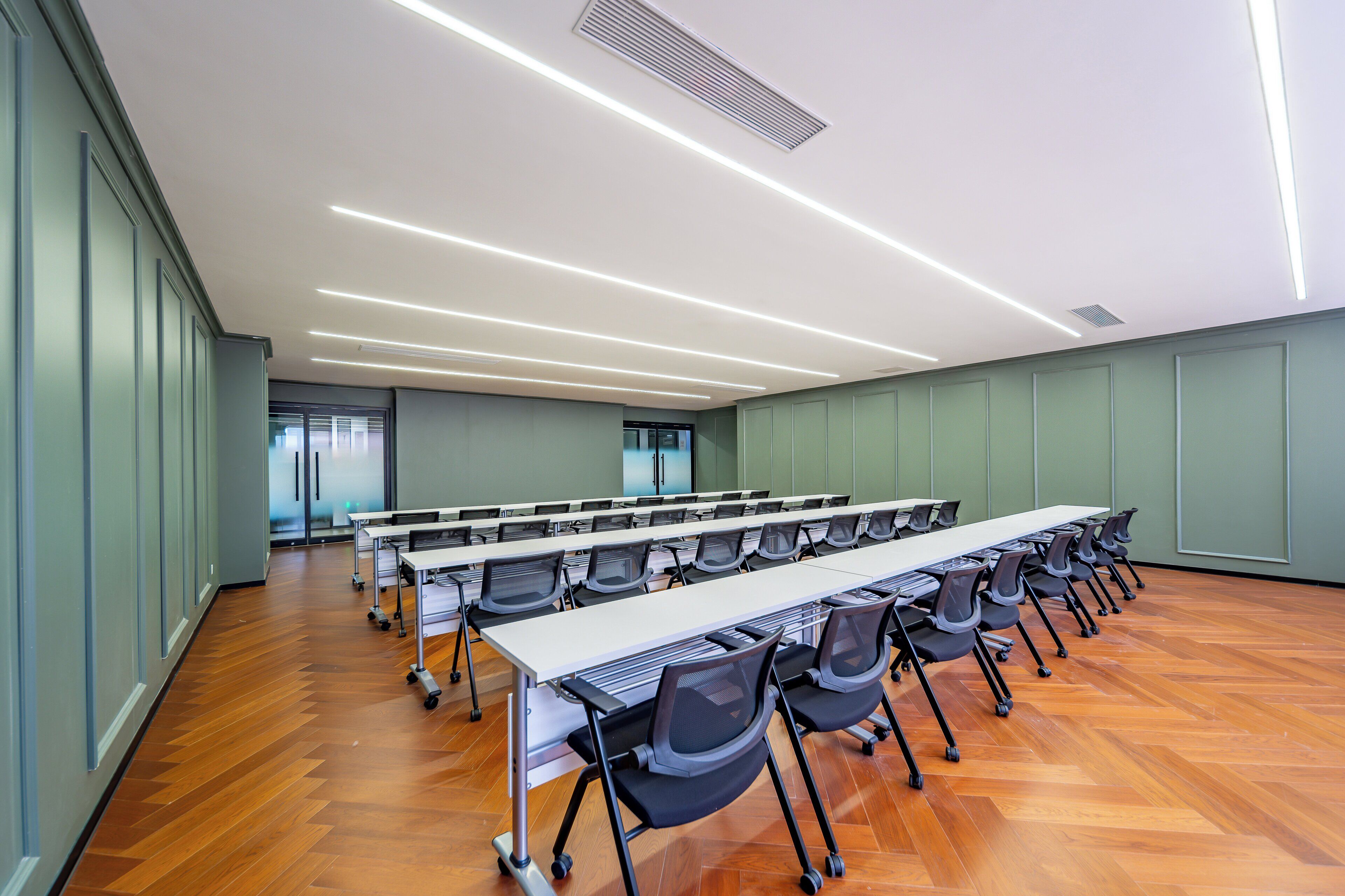 A conference room with a long table, chairs, and a wooden floor.