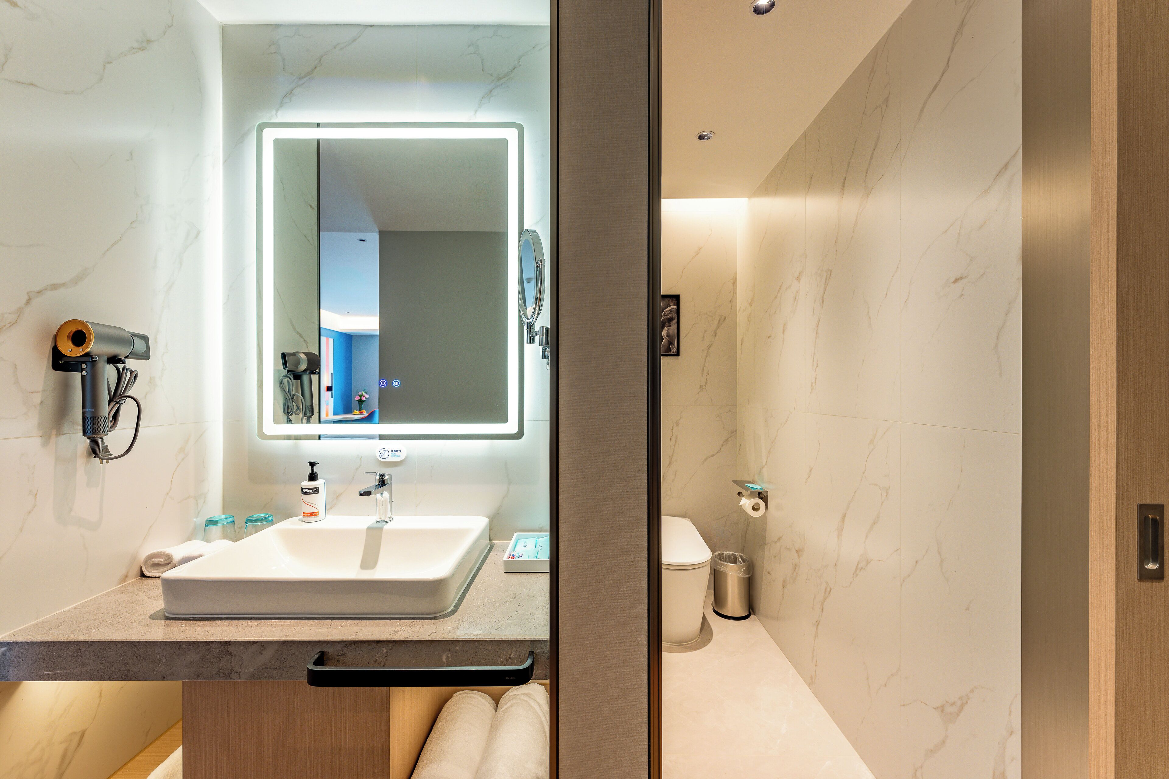 A modern bathroom with a large mirror, a sink, and a toilet.