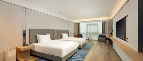 A modern hotel room with two beds, a desk, a TV, and a view of the city.