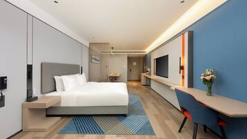 Ein modernes Hotelzimmer mit Bett, Schreibtisch, Stuhl und Fernseher.