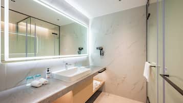 A modern bathroom with a large mirror, a sink, and a glass shower enclosure.