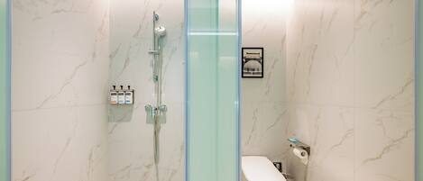 Une salle de bain moderne avec une douche à parois de verre, des toilettes et un mur en marbre.
