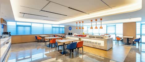 Un moderno vestíbulo de hotel con mostrador central, zona de estar y grandes ventanales.