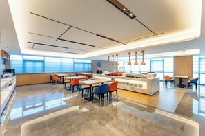 A modern hotel lobby with a central counter, seating area, and large windows.