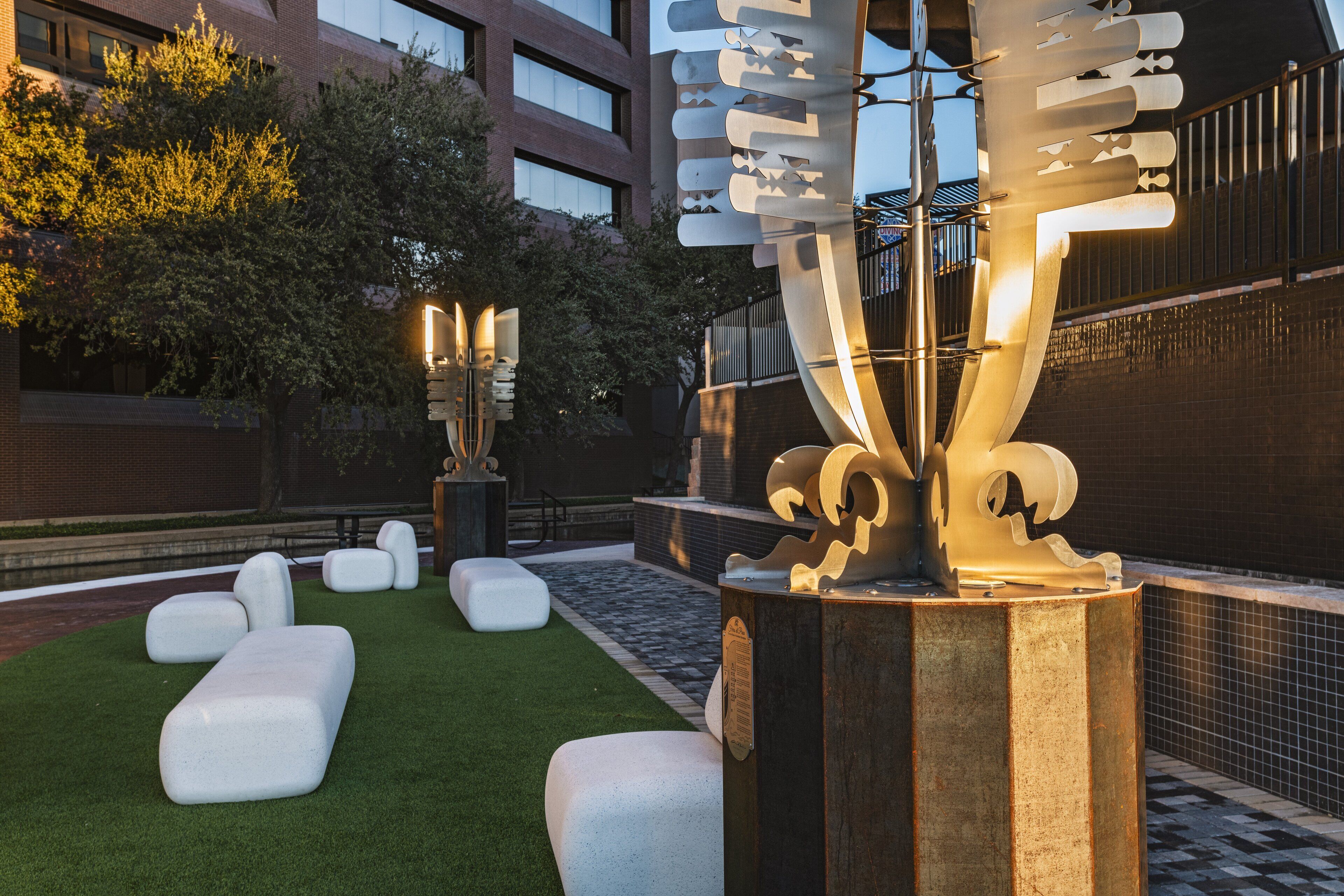 An outdoor seating area with white benches and a large illuminated sculpture.