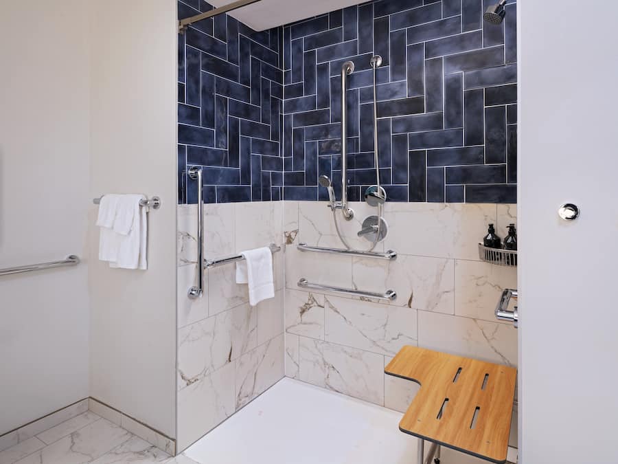 Une salle de bain moderne avec un espace douche, des carreaux de marbre et un meuble-lavabo en bois.