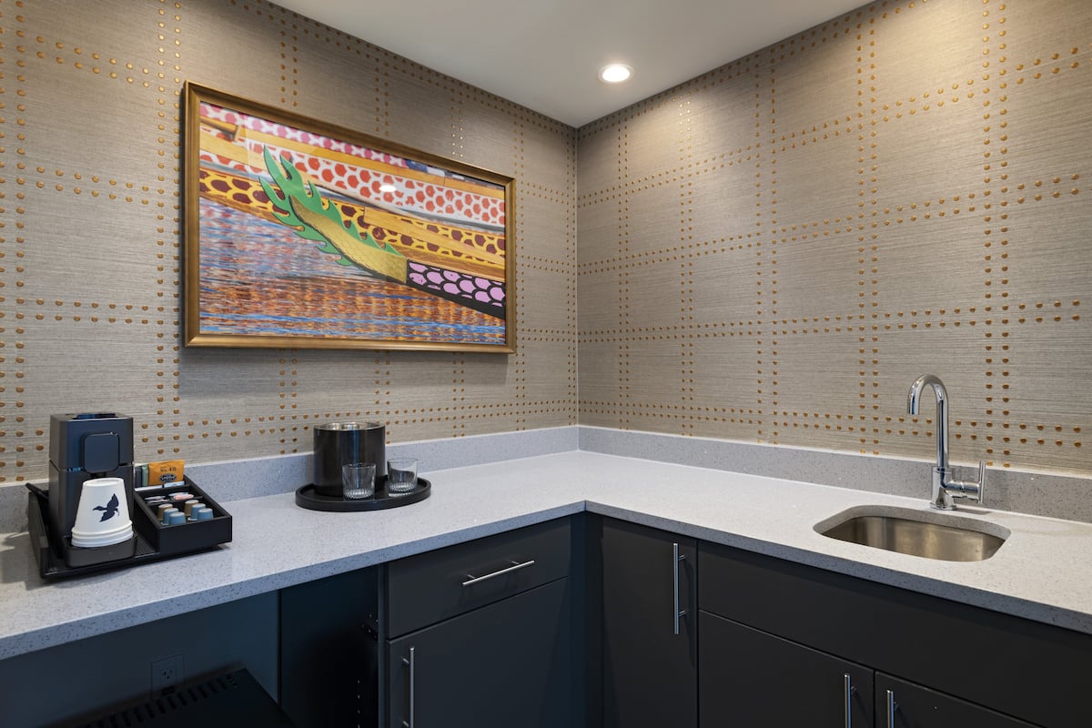 A modern kitchen with a coffee machine, a sink, and a decorative wall panel.