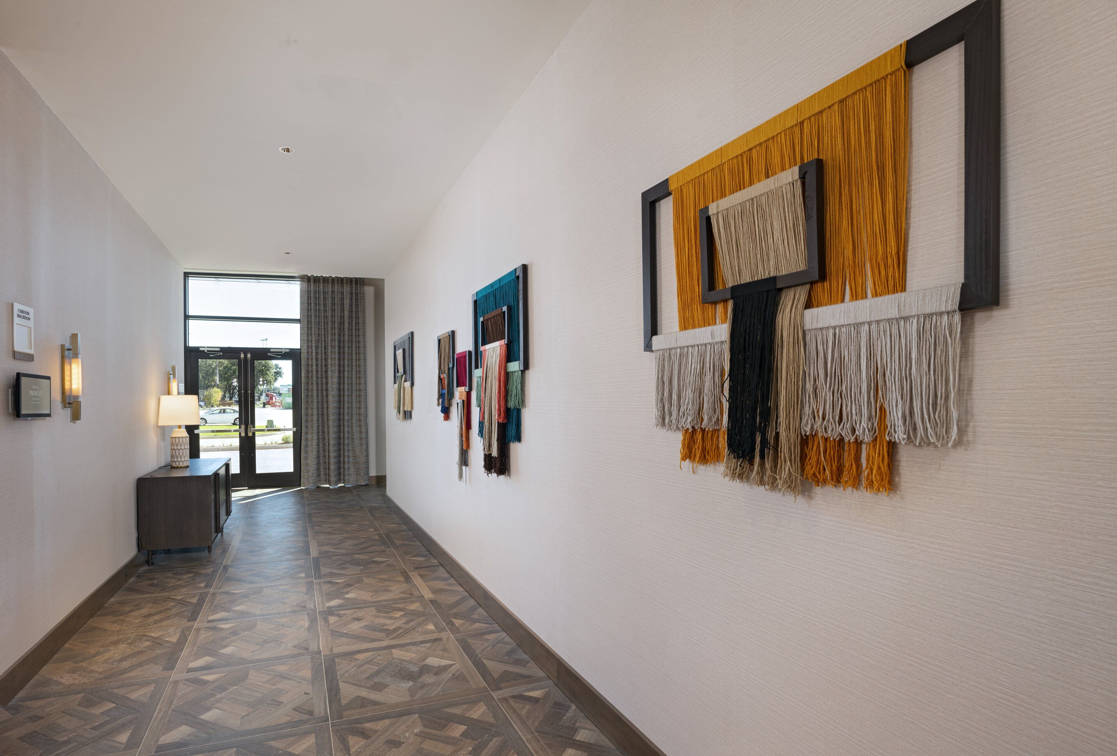 A hallway with patterned flooring, a lamp, and wall-mounted artwork.