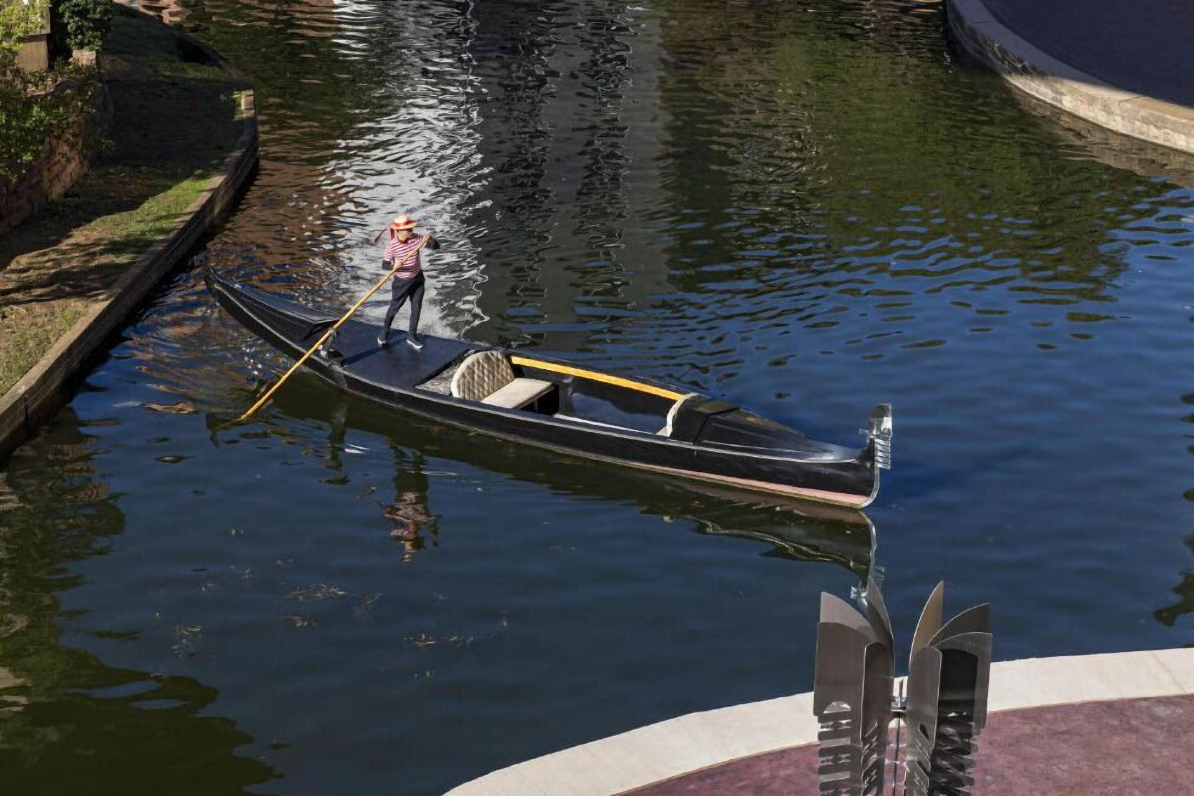 A narrow waterway with a small boat being towed by a person.