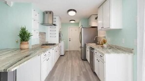 A modern kitchen with white cabinets, a marble countertop, and a central island. - Cool Ranch (Murfreesboro)