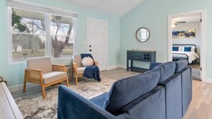 A room with a large window, a ceiling fan, a sofa, a chair, and a small table. - Cool Ranch (Murfreesboro)
