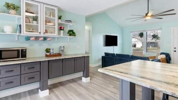 A modern kitchen with a built-in microwave, dark grey cabinets, and a wooden dining table. - Cool Ranch (Murfreesboro)