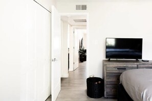 A hotel room with a bed, a TV on a wooden dresser, and a suitcase on the floor. - La Casa Maya: Modern 2bd/2br condo near Old Town. Can't beat this location!  (Scottsdale)