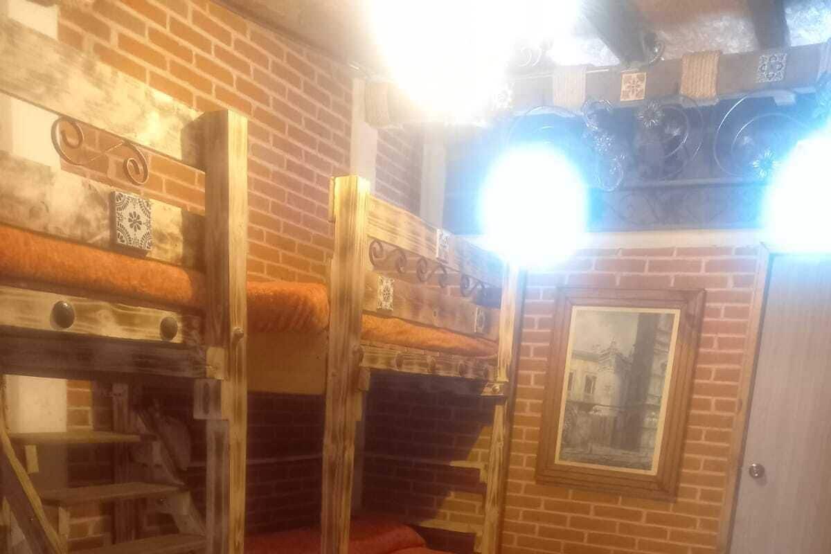 A room with bunk beds, a wooden ladder, a tiled floor, and a framed picture on the wall.