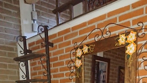 A wooden bench with a decorative mirror and a metal ladder against a brick wall. - HOSTAL EL REFUGIO (Puebla)