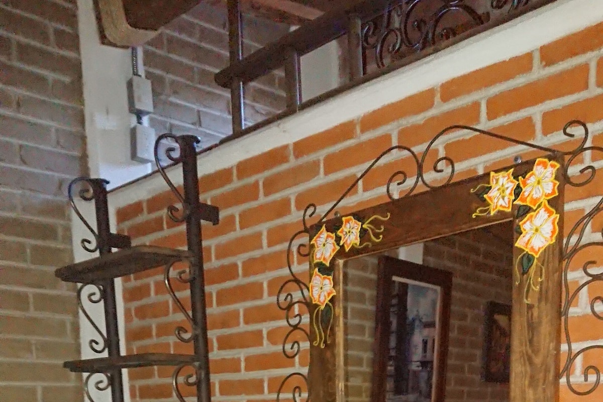 A wooden bench with a decorative mirror and a metal ladder against a brick wall.