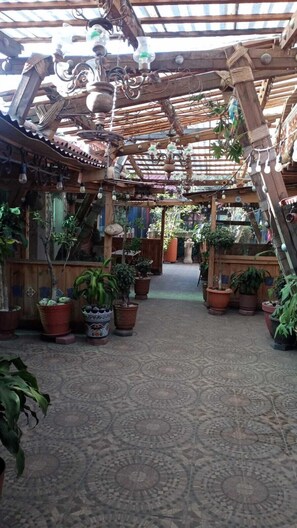 An indoor garden with a patterned floor, wooden beams, and various potted plants. - HOSTAL EL REFUGIO (Puebla)