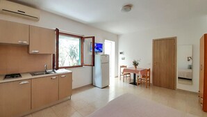 A compact kitchen with a window, a refrigerator, and a dining area with a table and chairs.