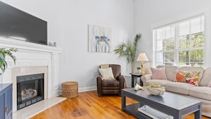 A living room with a fireplace, a sofa, a coffee table, and a television. - 2 miles from Holden Beach Dog Friendly, Family Friendly Sandy Feet Retreat! (Supply)