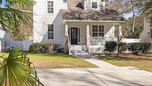 A two-story house with a front porch, a covered entryway, and a small front yard. - 2 miles from Holden Beach Dog Friendly, Family Friendly Sandy Feet Retreat! (Supply)