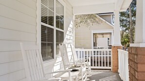 A porch with white wooden chairs and a white railing. - 2 miles from Holden Beach Dog Friendly, Family Friendly Sandy Feet Retreat! (Supply)