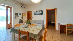 A dining area with a table set for four, a sofa, and a small table with a chair. There is a potted plant on the table and a painting on the wall. - 2 bedroom cozy apartment in Vieste (Vieste)