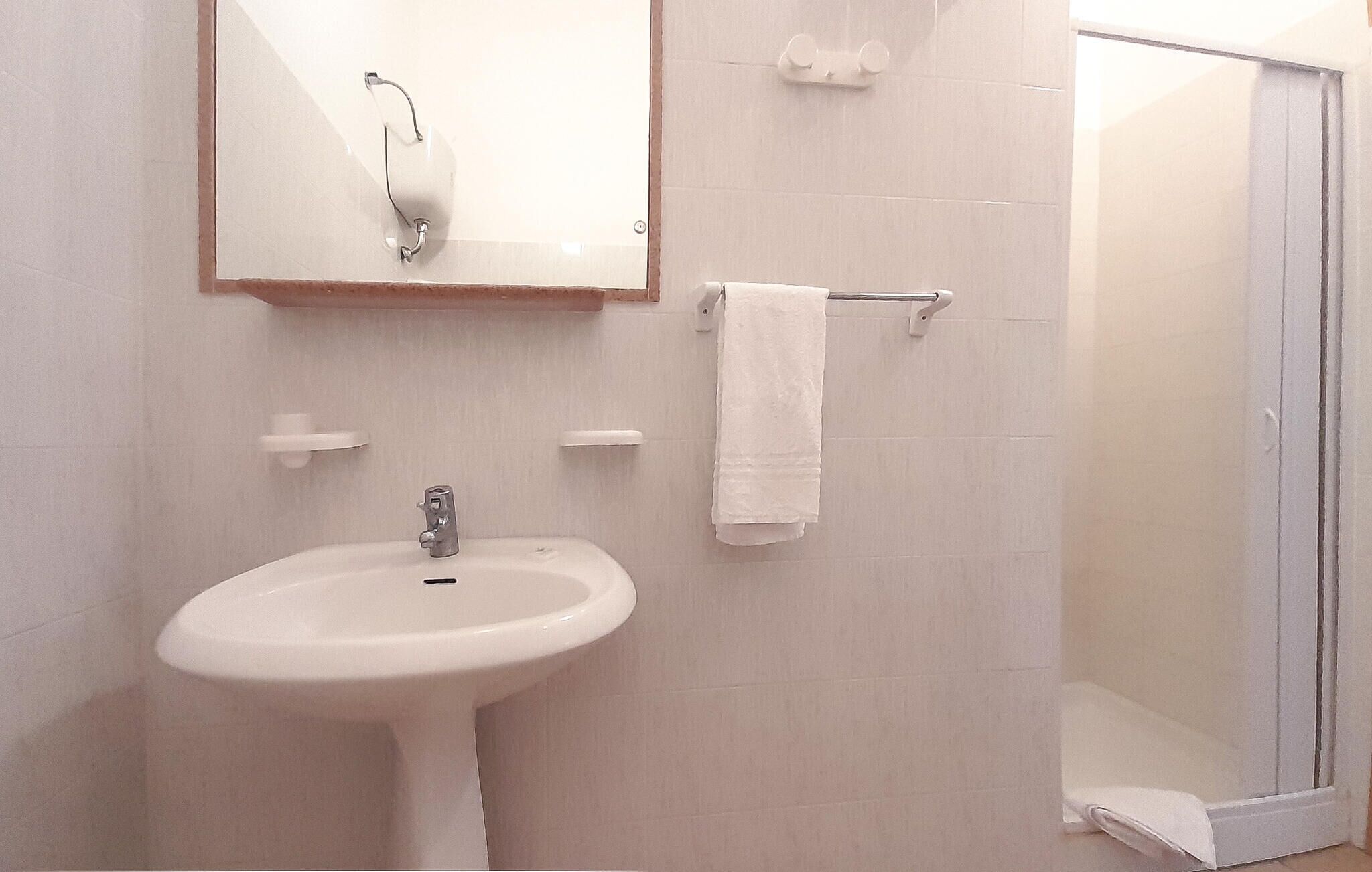 A bathroom with a white sink, a mirror, and a towel rack.
