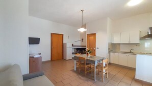 A compact living space with a dining area, kitchenette, and a TV mounted on the wall. - 2 bedroom cozy apartment in Vieste (Vieste)