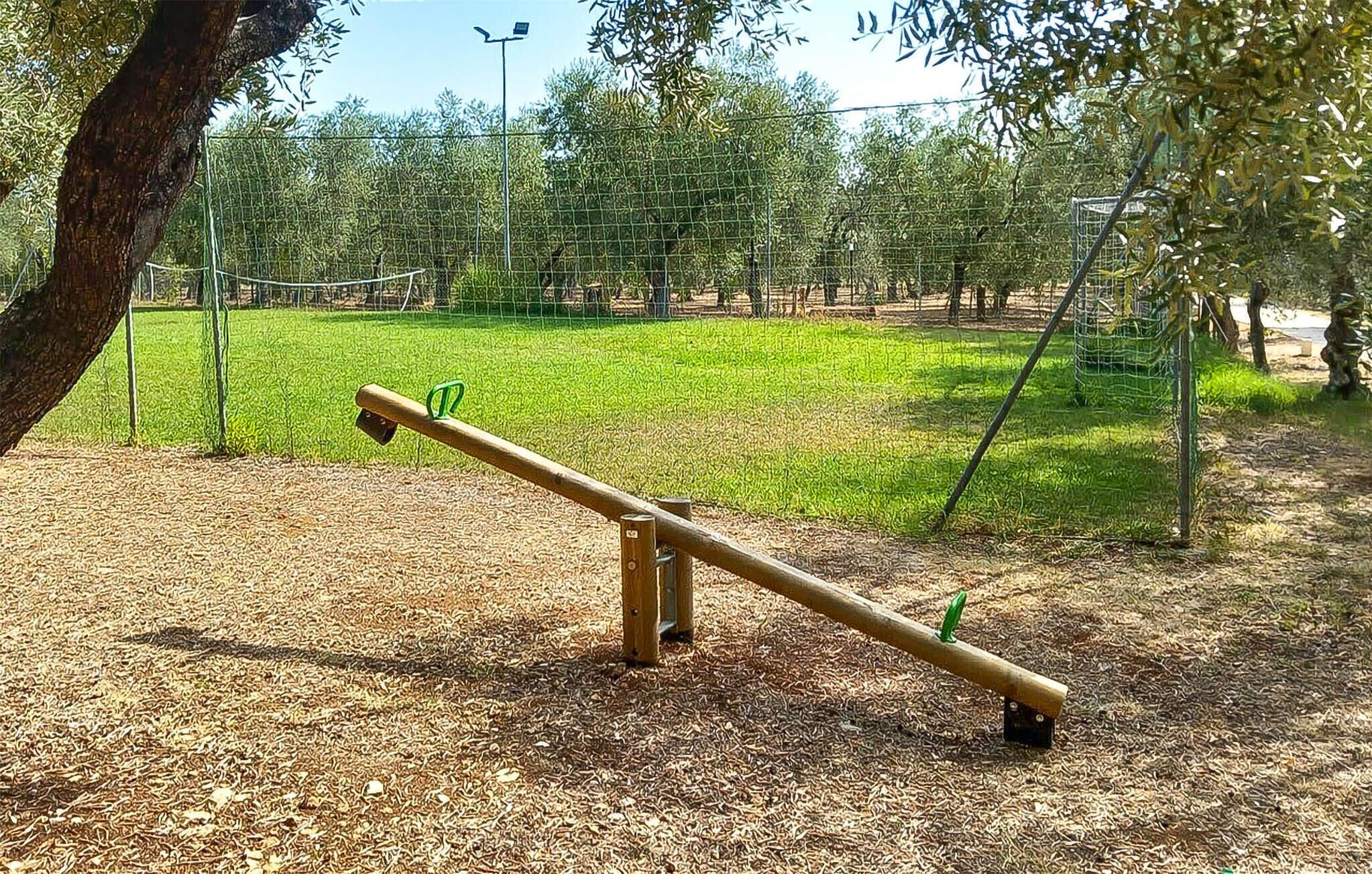 Eine Wippe in einem Park, im Hintergrund Grünflächen und Bäume.
