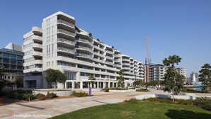A modern multi-story hotel with balconies, a landscaped courtyard, and a view of the surrounding urban area.