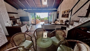 A cozy interior with wicker furniture, a glass-top table, and a view through a glass door to an outdoor area. - Tuscany, Ansedonia - Villa for 7 people with swimming pool (Ansedonia)