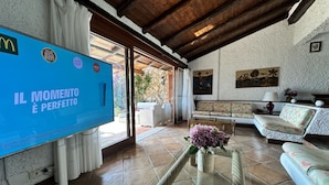 A living room with a television, sofa, and a coffee table with flowers. - Tuscany, Ansedonia - Villa for 7 people with swimming pool (Ansedonia)