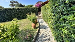 A stone pathway leading to a house with a wooden pergola, surrounded by well-maintained hedges and a potted plant. - Tuscany, Ansedonia - Villa for 7 people with swimming pool (Ansedonia)