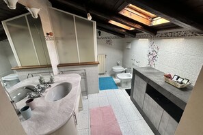 Een badkamer met een grote spiegel, een wastafel, een toilet en een douchetoilet.