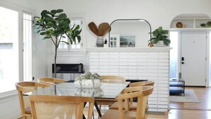 A dining area with a glass table, wooden chairs, a white brick fireplace, and potted plants. - Aliza Hotel (Venice)