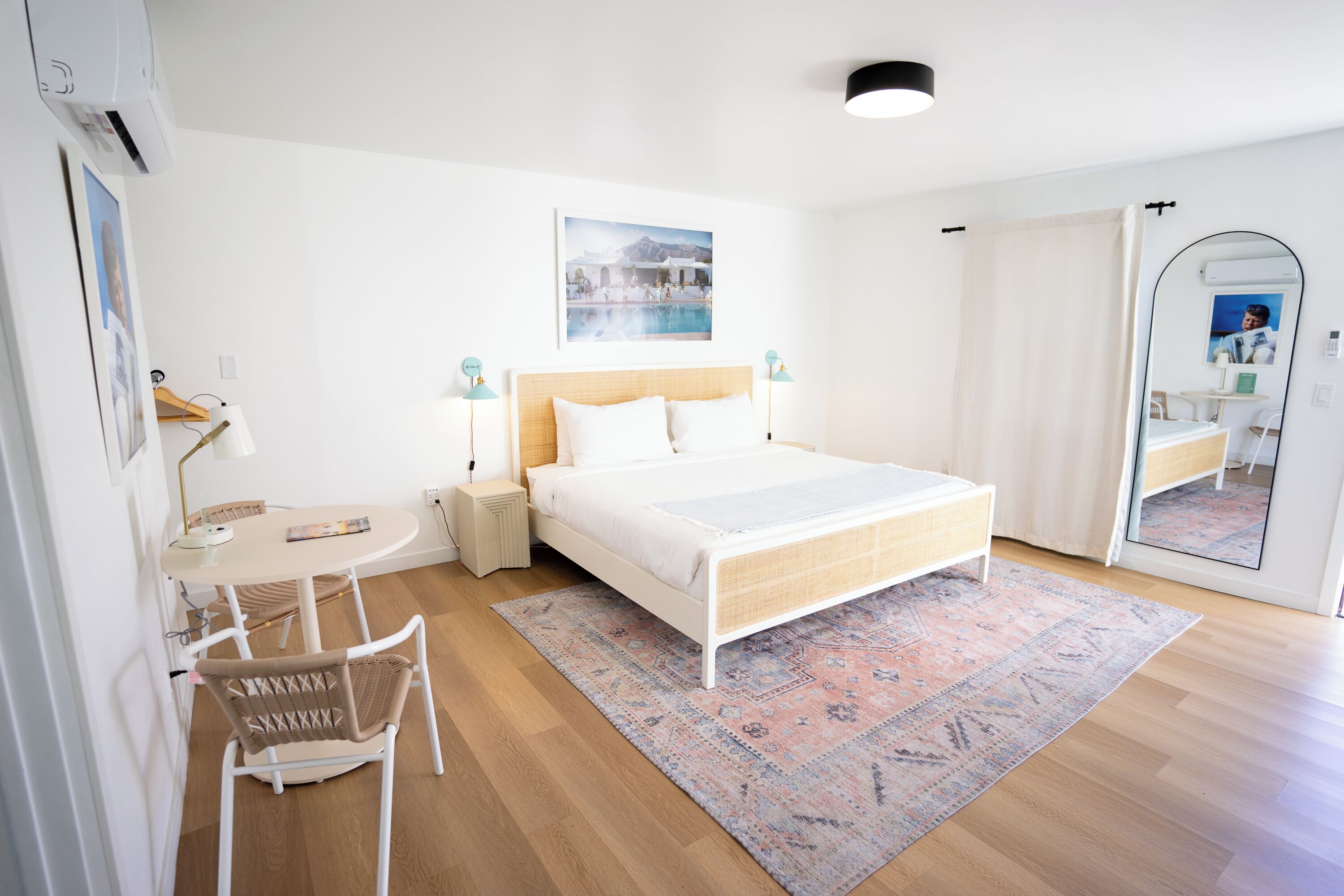 Een slaapkamer met een bed, nachtkastjes, een stoel, een bureau en een grote spiegel.