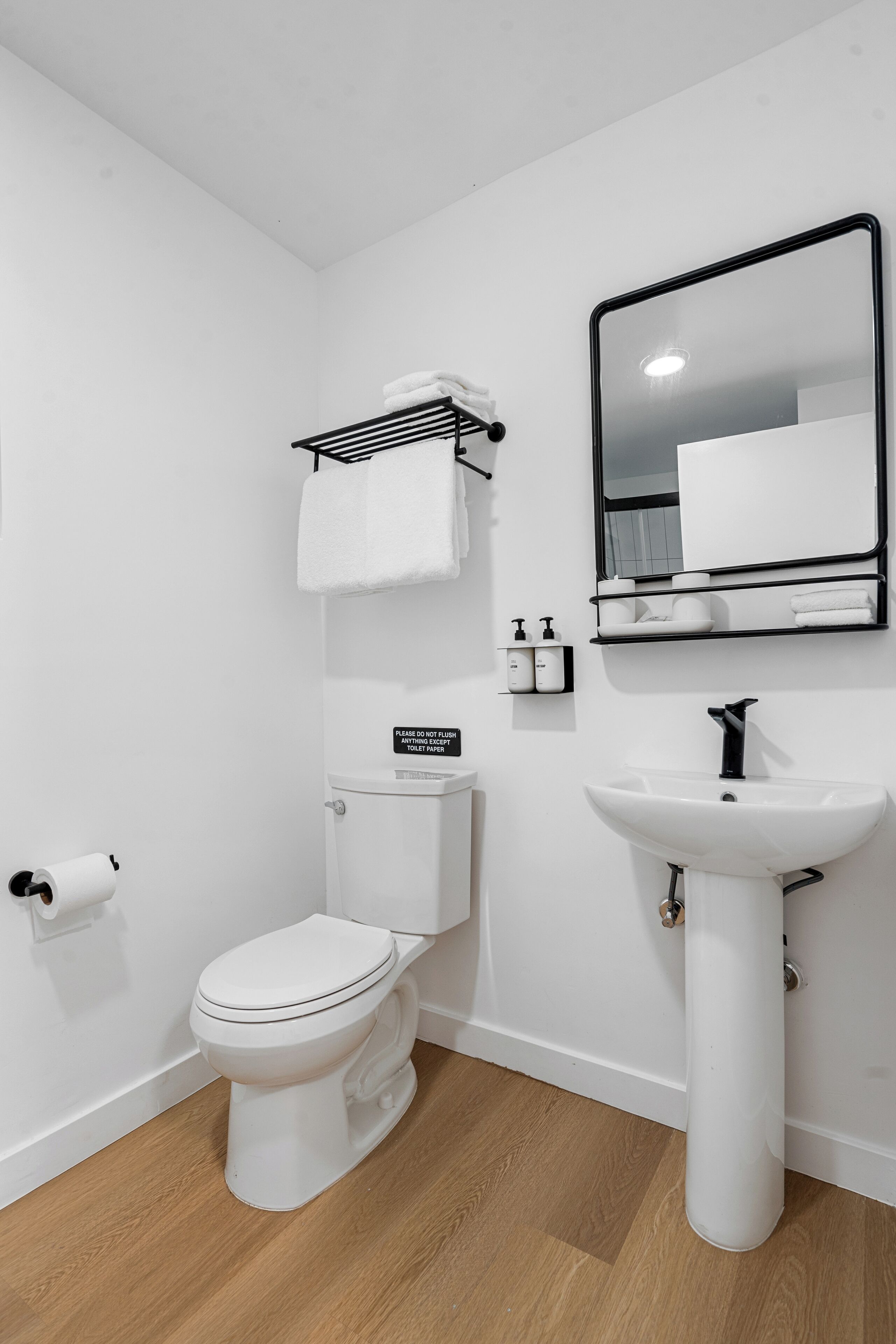 A modern bathroom with a toilet, sink, and mirror.