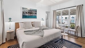 A modern hotel room with a large bed, a view of the pool, and a balcony with outdoor seating. - Aliza Hotel (Venice)