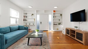 A modern living room with a blue sofa, a coffee table, and a TV mounted on the wall. - Aliza Hotel (Venice)