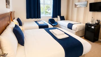 Hotellihuone, jossa on kaksi sänkyä, televisio ja ikkuna, jossa on verhot.