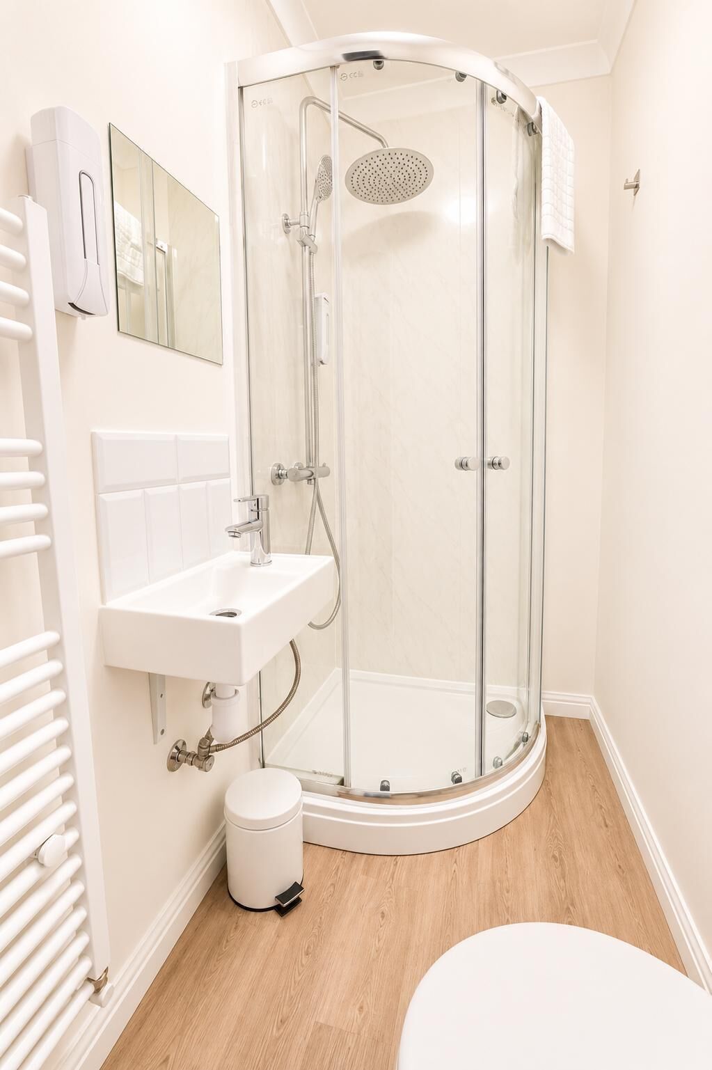 A modern bathroom with a glass-enclosed shower, a white sink, and a toilet.