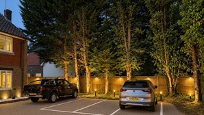 A parking area with two cars, a brick driveway, and a wooden fence. - High Trees Gatwick Guest House  (Horley)