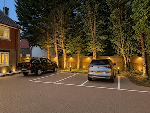 A parking area with two cars, a brick driveway, and a wooden fence. - High Trees Gatwick Guest House  (Horley)