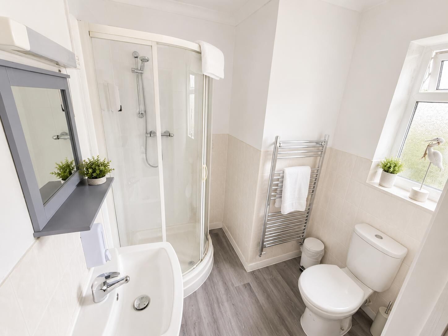 A modern bathroom with a glass-enclosed shower, a white sink, and a toilet.