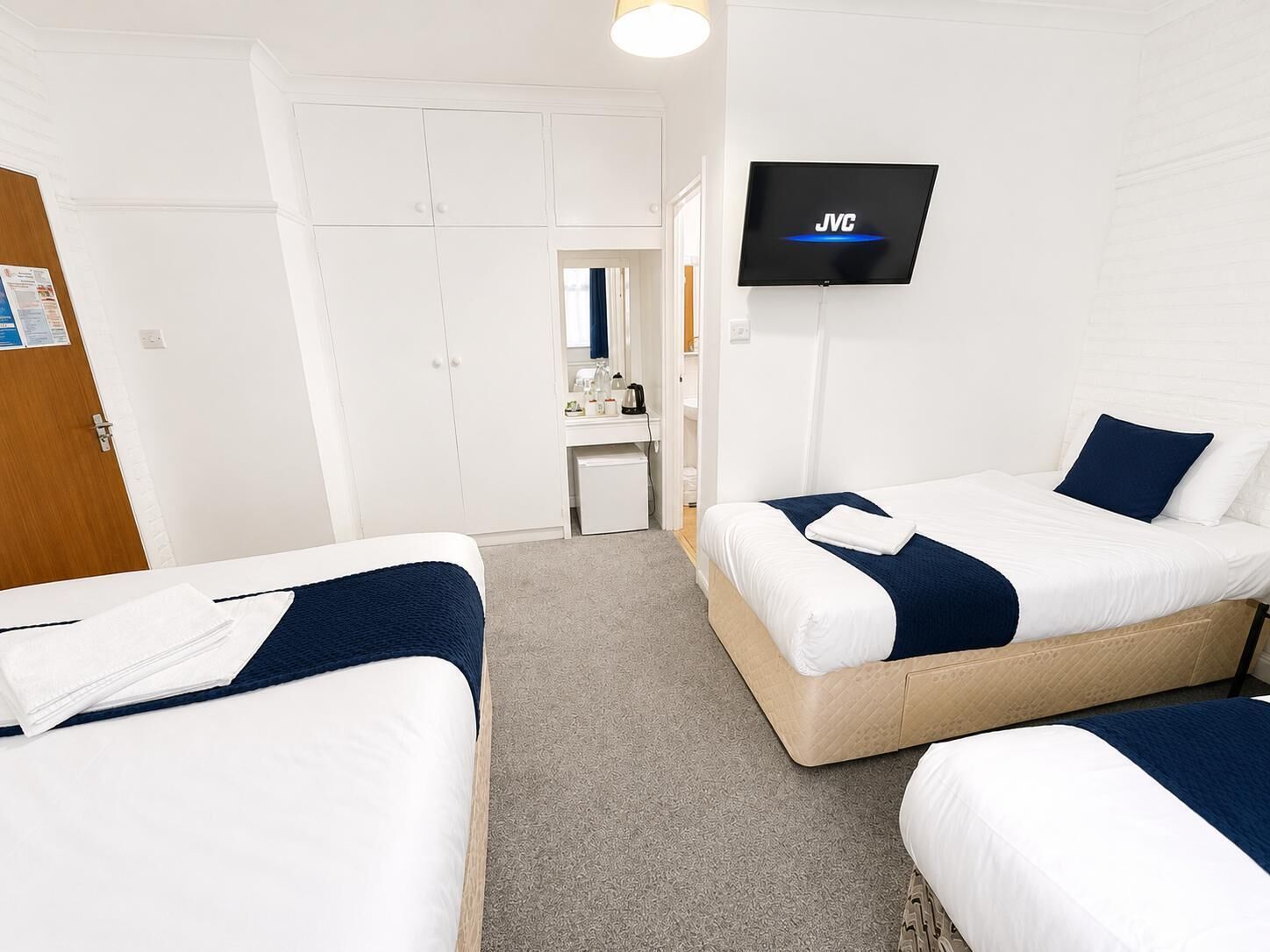 A hotel room with two beds, a TV, a desk, and a wardrobe.