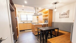 Una cucina compatta con mobili in legno, un piano cottura integrato e una zona pranzo con sgabelli.