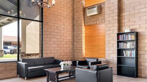 Um lobby moderno com parede de tijolos, sofás de couro, uma mesa de centro com flores e uma estante de livros.