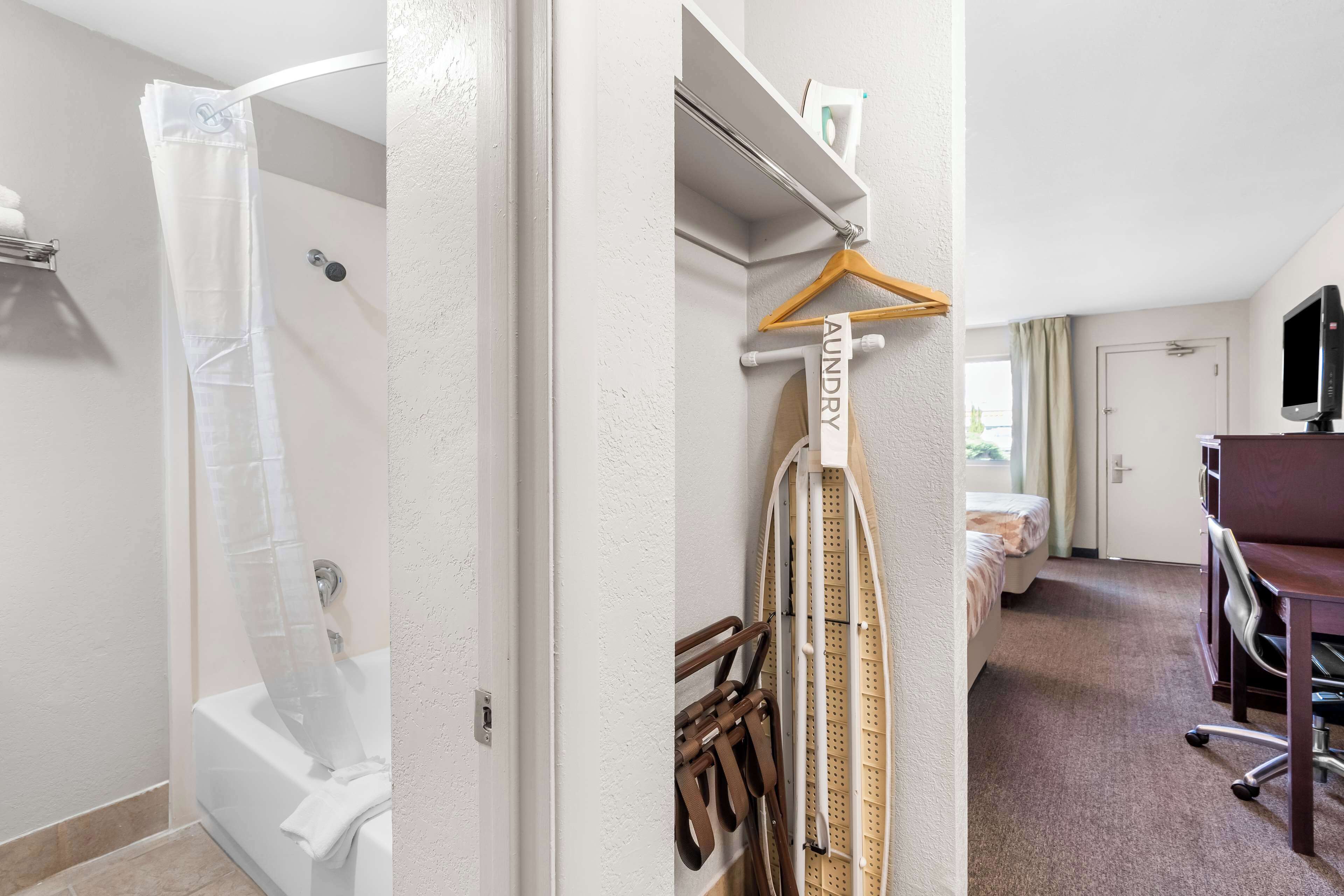 Habitación de hotel con ducha, cama, escritorio y silla, y televisión.