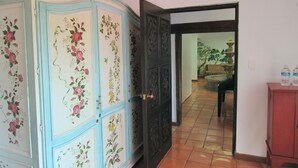 Ein Zimmer mit einem großen, blauen Schrank mit floralem Dekor, einer Holztür und einem gefliesten Boden.